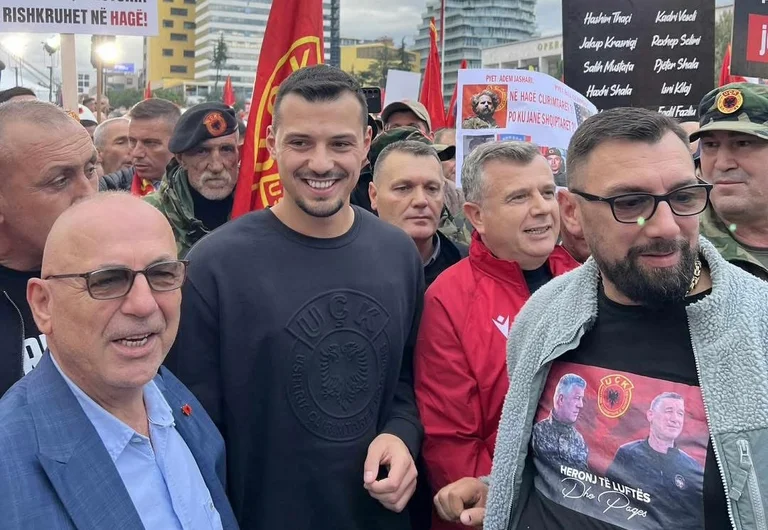 Andrew Thaci smiling amid protest in Tirana