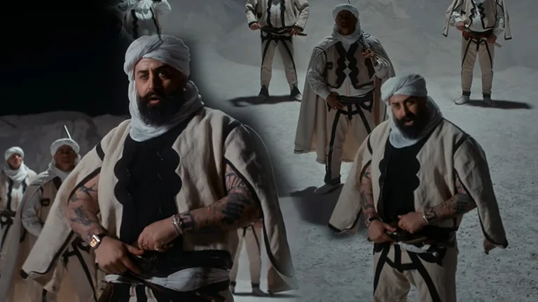 Getoar Selimi in traditional dress on the new clip, appears with a white shawl on his head