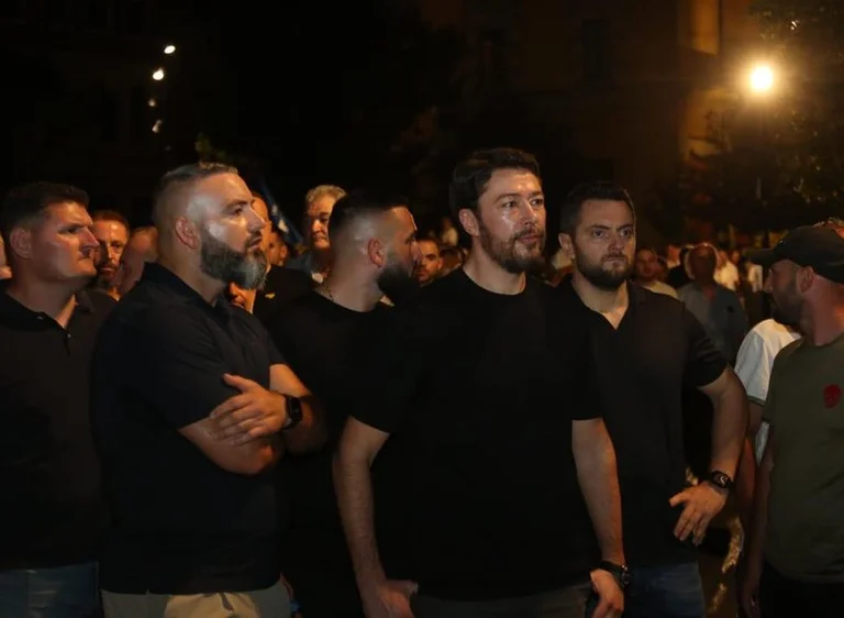 Shkelzen Berisha en protestation entouré d'un troupeau de gardes du corps