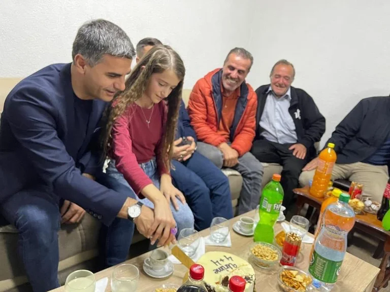 Tahiri wird mit Dessert in den serbischen Familien begrüßt, verspricht, dass er immer mit ihnen sein wird, um die Stadt zu fördern