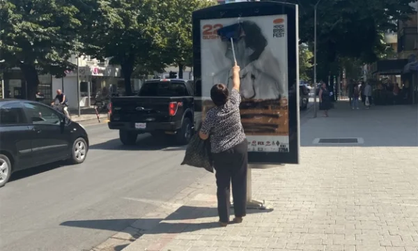 Një grua në Tiranë pastron reklamën e shkarravitur ku është fshirë fytyra e Goran Bregoviqit