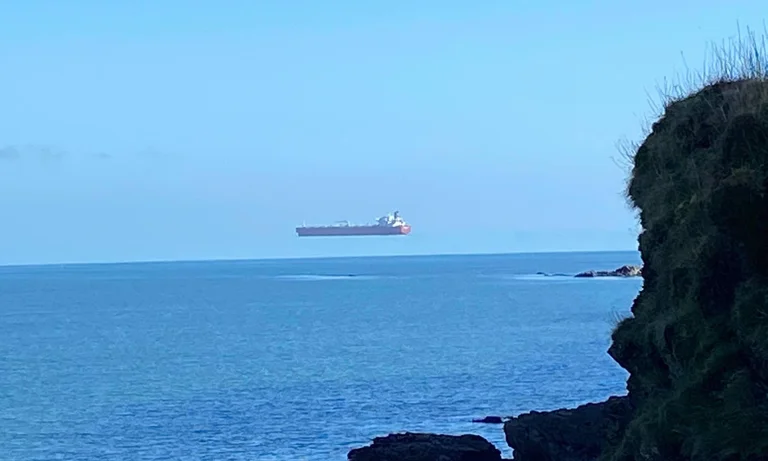 El hombre de pie está sorprendido por ver un barco flotando sobre el agua