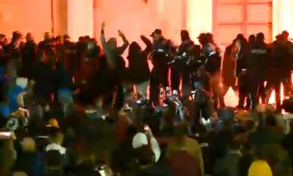 Un poliziotto guarda la protesta di Tirana