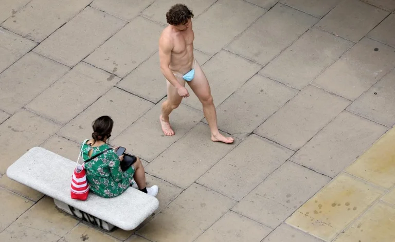 Un uomo che cammina per le strade di Londra indossa una maschera invece dei pantaloni